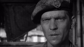 Movie still from “King Rat” (1965), directed by Bryan Forbes – A man wearing a military uniform and a hat; Close Up shot, Low angle