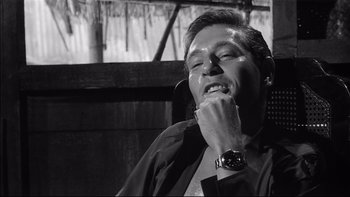 Movie still from “King Rat” (1965), directed by Bryan Forbes – A black and white photo of a man talking on a phone; Close Up shot, Low angle