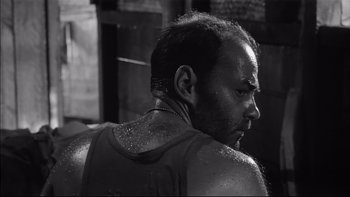 Movie still from “King Rat” (1965), directed by Bryan Forbes – Black and white photograph of a man with sweat on his face; Close Up shot, Low angle
