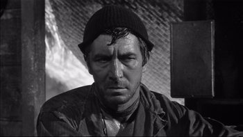 Movie still from “King Rat” (1965), directed by Bryan Forbes – Black and white photograph of a man wearing a hat; Close Up shot, High angle
