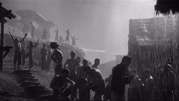 Movie still from “King Rat” (1965), directed by Bryan Forbes – A black and white photo of a group of men in the rain; Extreme Wide shot, Low angle