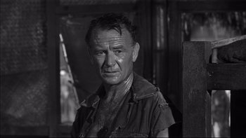 Movie still from “King Rat” (1965), directed by Bryan Forbes – An older man with a wet shirt on his face; Close Up shot, Over the shoulder angle