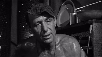 Movie still from “King Rat” (1965), directed by Bryan Forbes – A black and white photo of a man with a hat on; Close Up shot, Low angle