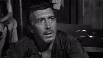 Movie still from “King Rat” (1965), directed by Bryan Forbes – Black and white photograph of a man looking at the camera; Close Up shot, Low angle