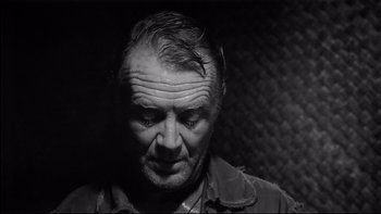 Movie still from “King Rat” (1965), directed by Bryan Forbes – An older man is looking down at his face; Close Up shot, Over the shoulder angle