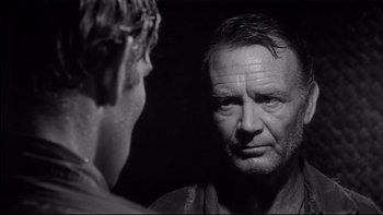 Movie still from “King Rat” (1965), directed by Bryan Forbes – A man looking into a mirror while standing next to another man; Close Up shot, Over the shoulder angle