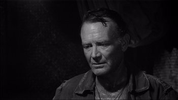 Movie still from “King Rat” (1965), directed by Bryan Forbes – Black and white photograph of a man with wet hair; Close Up shot, Over the shoulder angle