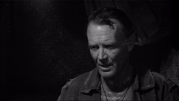 Movie still from “King Rat” (1965), directed by Bryan Forbes – Black and white photograph of a man with a beard; Close Up shot, Over the shoulder angle