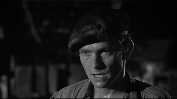 Movie still from “King Rat” (1965), directed by Bryan Forbes – A black and white photo of a man wearing a hat; Close Up shot, Low angle