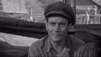 Movie still from “King Rat” (1965), directed by Bryan Forbes – A man wearing a hat is looking at the camera; Close Up shot, Low angle