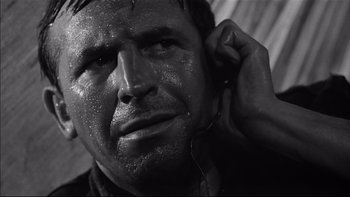 Movie still from “King Rat” (1965), directed by Bryan Forbes – Black and white photograph of a man listening to music; Close Up shot, Low angle