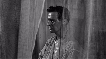 Movie still from “King Rat” (1965), directed by Bryan Forbes – Black and white photograph of a man looking out of a window; Close Up shot, Low angle