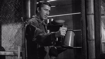 Movie still from “King Rat” (1965), directed by Bryan Forbes – A man holding a pot in his hands; Medium shot, Low angle