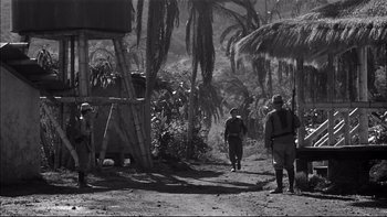 Movie still from “King Rat” (1965), directed by Bryan Forbes – A black - and - white photo of people walking down a dirt road; Wide shot, Low angle