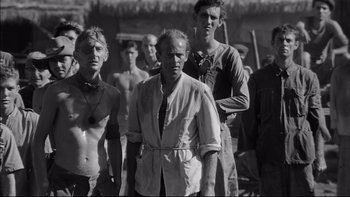 Movie still from “King Rat” (1965), directed by Bryan Forbes – A black and white photo of a group of men; Medium shot, Low angle