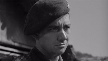 Movie still from “King Rat” (1965), directed by Bryan Forbes – Black and white photograph of a man in a military uniform; Close Up shot, Low angle