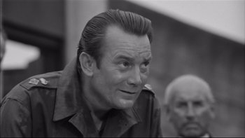 Movie still from “King Rat” (1965), directed by Bryan Forbes – An older man in a military uniform looking to his left; Close Up shot, Over the shoulder angle