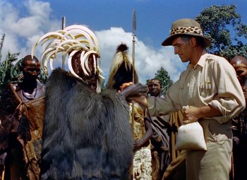 Movie still from “King Solomon's Mines” (1950), directed by Andrew Marton – A man in a costume is standing next to a man in an animal costume; Medium shot, Over the shoulder angle