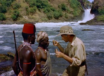 Movie still from “King Solomon's Mines” (1950), directed by Andrew Marton – A man in a hat is talking to two men in traditional clothing; Medium shot, Over the shoulder angle