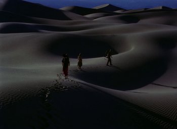 Movie still from “King Solomon's Mines” (1950), directed by Andrew Marton – A group of people walking in the desert at night; Extreme Wide shot, High angle