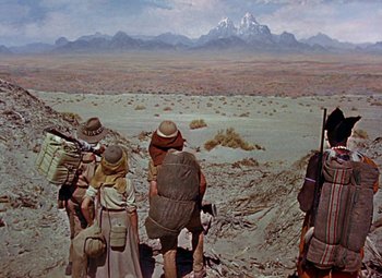 Movie still from “King Solomon's Mines” (1950), directed by Andrew Marton – A group of people standing on top of a dirt field; Wide shot, High angle