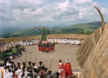 Movie still from “King Solomon's Mines” (1950), directed by Andrew Marton – A group of people standing in a circle on top of a dirt field; Extreme Wide shot, High angle