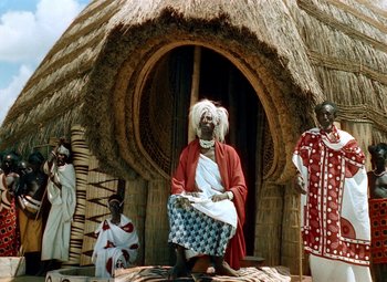 Movie still from “King Solomon's Mines” (1950), directed by Andrew Marton – A group of people standing in front of a hut; Wide shot, Low angle
