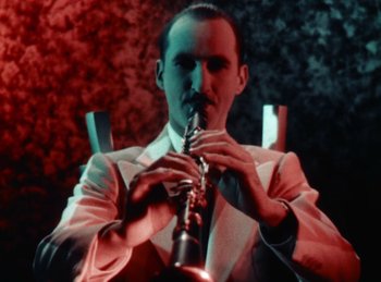 Movie still from “King of Jazz” (1930), directed by Walter Lantz – A man in a white suit playing a saxophone; Close Up shot, Low angle