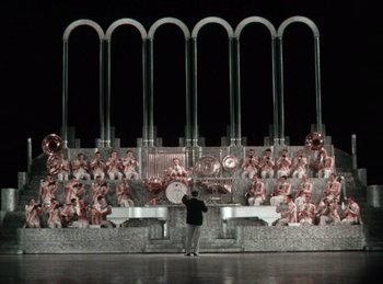 Movie still from “King of Jazz” (1930), directed by Walter Lantz – A man standing in front of a crowd of people on a stage; Extreme Wide shot, High angle