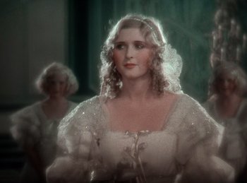 Movie still from “King of Jazz” (1930), directed by Walter Lantz – A woman in a white dress is standing in front of two other women; Close Up shot, Over the shoulder angle
