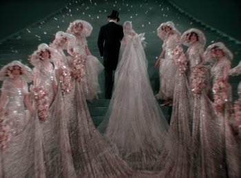 Movie still from “King of Jazz” (1930), directed by Walter Lantz – A group of people in wedding dresses standing on a staircase; Wide shot, High angle