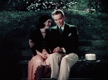 Movie still from “King of Jazz” (1930), directed by Walter Lantz – A man and a woman sitting on a park bench; Medium shot, High angle