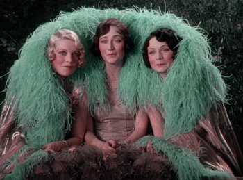 Movie still from “King of Jazz” (1930), directed by Walter Lantz – A group of women sitting next to each other wearing feathers; Medium shot, High angle