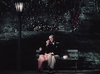 Movie still from “King of Jazz” (1930), directed by Walter Lantz – A man and a woman sitting on a park bench; Wide shot, High angle