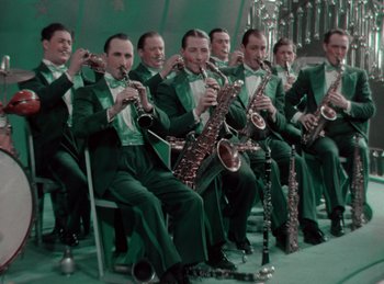 Movie still from “King of Jazz” (1930), directed by Walter Lantz – A group of men in green tuxedos holding their instruments; Medium shot, High angle
