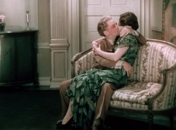 Movie still from “King of Jazz” (1930), directed by Walter Lantz – Two women sitting on a couch kissing each other; Wide shot, High angle