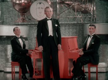 Movie still from “King of Jazz” (1930), directed by Walter Lantz – Three men in tuxedos sitting on chairs in a room; Medium shot, High angle
