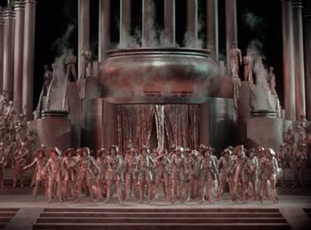 Movie still from “King of Jazz” (1930), directed by Walter Lantz – A large group of people standing in front of a building; Extreme Wide shot, High angle