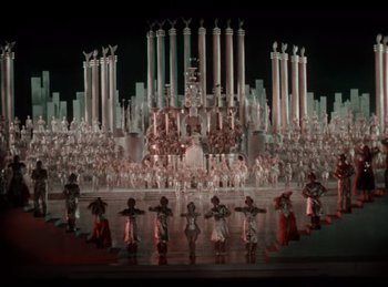 Movie still from “King of Jazz” (1930), directed by Walter Lantz – A group of people standing in front of a building with candles; Extreme Wide shot, High angle