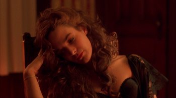 Movie still from “King of New York” (1990), directed by Abel Ferrara – A woman with long curly brown hair sitting in a room; Close Up shot, High angle