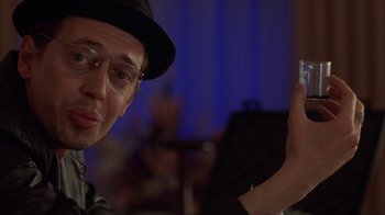 Movie still from “King of New York” (1990), directed by Abel Ferrara – A man in a hat and glasses holding a cell phone; Close Up shot, Over the shoulder angle