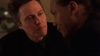 Movie still from “King of New York” (1990), directed by Abel Ferrara – A man looking at another man in a black suit; Close Up shot, Over the shoulder angle