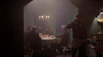 Movie still from “King of New York” (1990), directed by Abel Ferrara – A group of people sitting around a table; Wide shot, Low angle