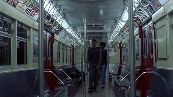 Movie still from “King of New York” (1990), directed by Abel Ferrara – Two men standing on a subway train looking at the camera; Wide shot, High angle