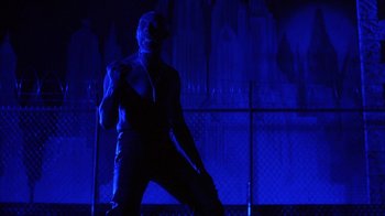 Movie still from “King of New York” (1990), directed by Abel Ferrara – A man standing in front of a chain link fence; Medium shot, Low angle