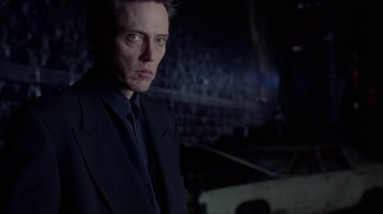 Movie still from “King of New York” (1990), directed by Abel Ferrara – A man wearing a suit and tie standing in a dark room; Close Up shot, Low angle