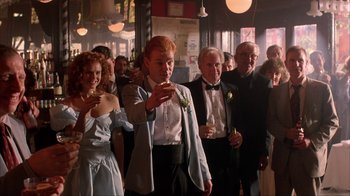 Movie still from “King of New York” (1990), directed by Abel Ferrara – A group of people standing in a room with drinks; Medium shot, Low angle