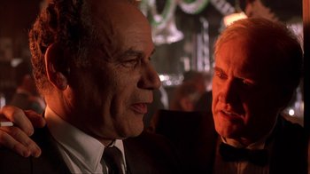 Movie still from “King of New York” (1990), directed by Abel Ferrara – Two men in suits talking to each other in a bar; Close Up shot, Low angle