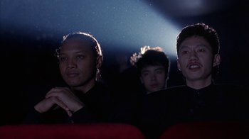 Movie still from “King of New York” (1990), directed by Abel Ferrara – A group of people sitting in a movie theater; Close Up shot, Low angle