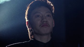 Movie still from “King of New York” (1990), directed by Abel Ferrara – A man with long black hair looking up at the sky; Close Up shot, Low angle